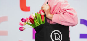 Person with flowers in a Drama Queen branded bag