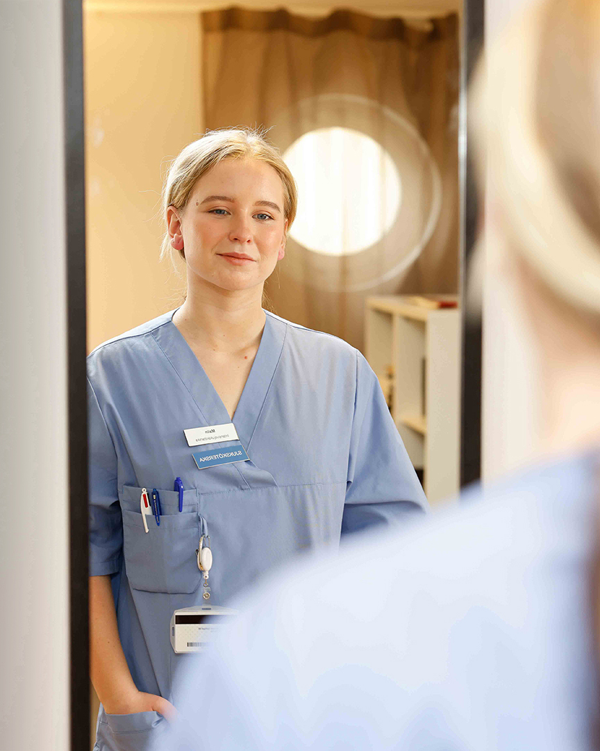 Blonde girl in nurse clothes looking at herself in the mirror.