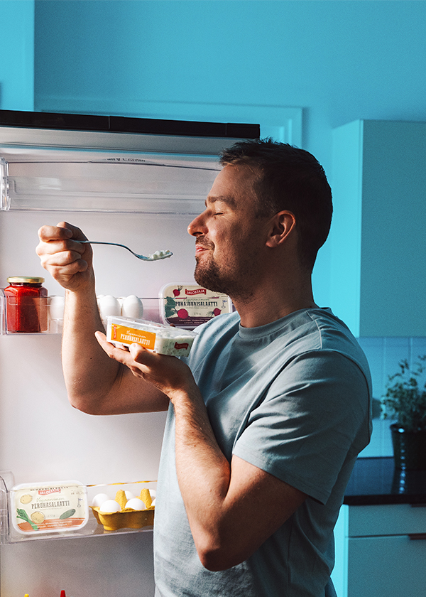A image of a man opening the refrigerator and eating a Jalostaja salad.